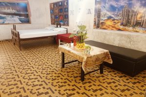 The Vayu Suite (Room 103) at Hotel Kalzug featuring a Queen-size bed (60x78 inches), a 3-seater sofa, and a dining table for a comfortable luxury stay.