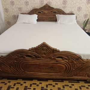 Front view of the super king bed in Radha Krish Suite Room 102, featuring a cozy 7-inch mattress for a comfortable stay at Hotel Kalzug.